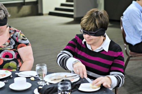An attendee dines with a blindfold on.