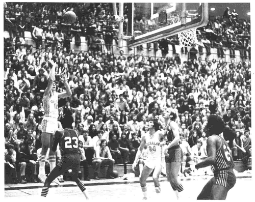 Forward Phil Goggins in the #12 jersey throws the basketball towards the net.