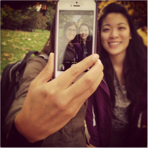 Two students snap a pic with a cell phone.