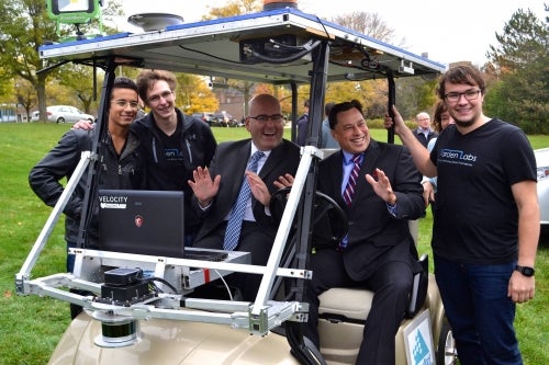 Minister Del Duca and Minister Duguid ride in a Varden Labs golf cart.