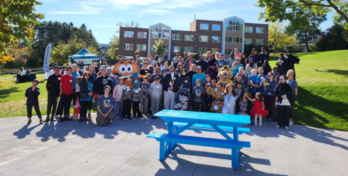 Attendees at the Ride for Refuge event at United College pose with Toasty and King Warrior.