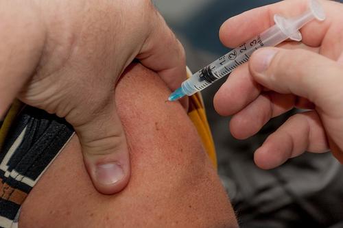 A needle being injected into a person's shoulder.