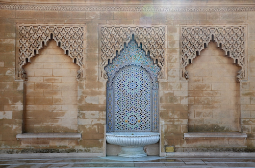A tiled fountain with three recessed alcoves with stylized archways.