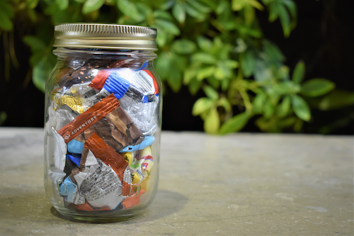 A mason jar filled with bits of trash in front of the Environment Living Wall.