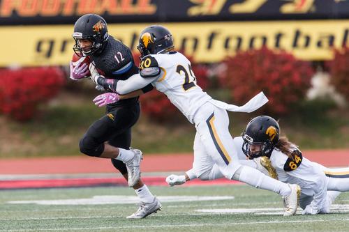Two Waterloo Warriors players attempt to tackle a Guelph Gryphon.