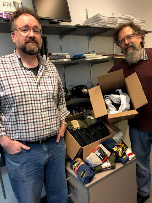 Dr. Scott Campbell (l) and Dr. Cameron Shelley (r) of the University of Waterloo’s interdisciplinary teaching centre, the Centre for Society, Technology and Values, with 64 pairs of socks collected for Toasty Toes. Photo by admin assistant Wendy Stocker.