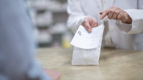 A pharmacist explains the prescription in a bag to a customer.