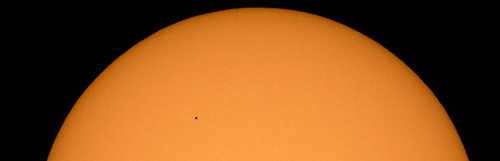 An image of the planet Mercury as a speck against the backdrop of the Sun.