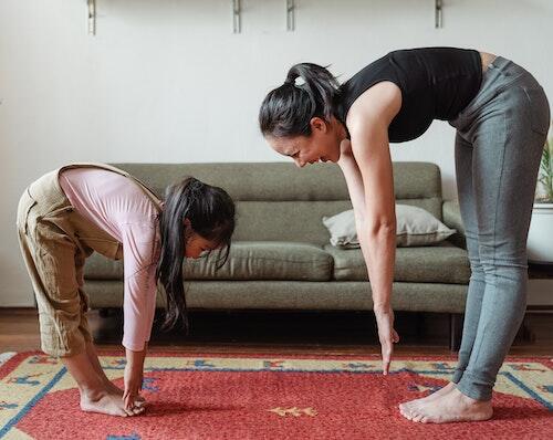 A woman and a child bend over to touch their toes.