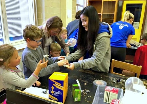 A female volunteer interacts with children at the Science Open House.