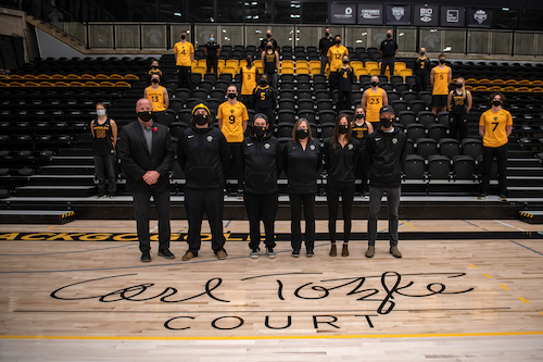 Athletics staff, wearing masks, stand atop the new Carl Totzke Court.