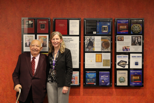 Adel Sedra stands with Dean Mary Wells in front of the commemorative bookshelf showing editions of his famous textbook.