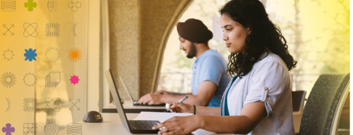 Two people type on laptops.