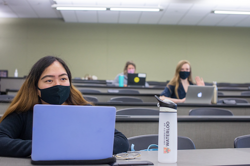 Students in a lecture hall wearing masks.