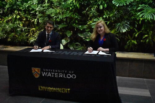 NAVBLUE and WISA representatives sign the agreement in front of the living wall in Environment 3.