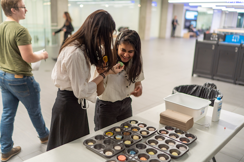 Students share a laugh as they inspect handmade soaps at the design studio event.