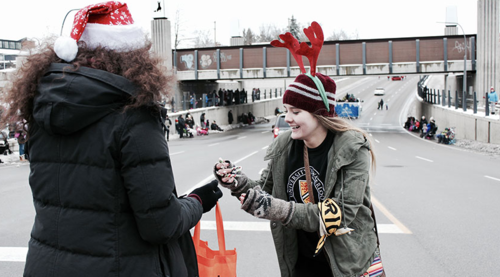 A Waterloo volunteer wearing reindeer antlers hands out candy canes along the parade route.