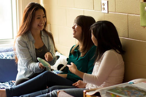 Three female upper-year students laughing in a residence room.