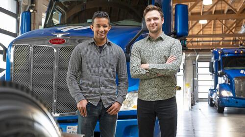 Alex Rodrigues, left, and Brandon Moak, co-founders of Embark Technology, stand in front of their autonomous trucks.