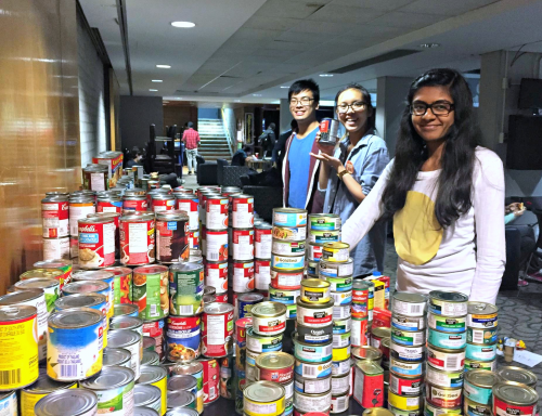 Smiling student volunteers stack canned goods as part of Trick or Eat.