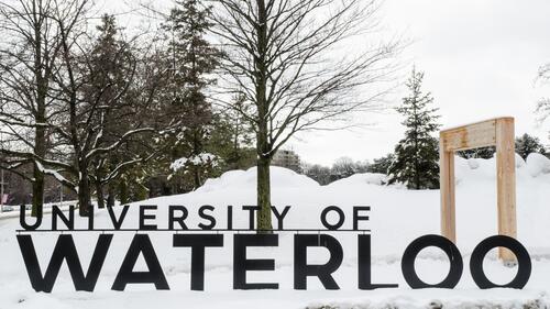 The University of Waterloo sign in winter with snow all around.