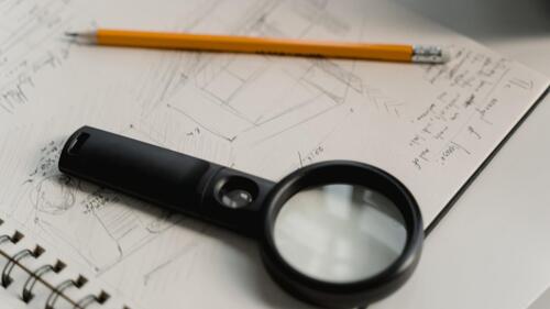An architect's sketch with pencil and magnifying glass.
