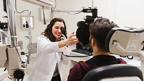 An optometrist performs an eye exam on a patient.