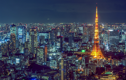 The skyline of Tokyo, Japan at night with the famous Tokyo Tower lit up in orange.