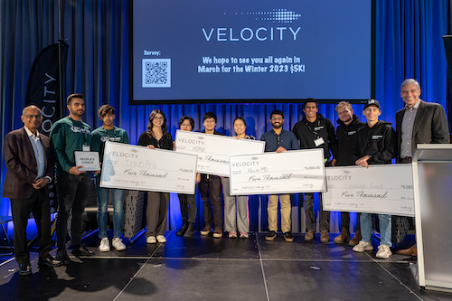 President Vivek Goel, Velocity Director John Dick, and the Velocity $5K winners on stage with oversized cheques.