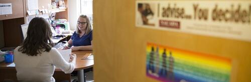 An advisor speaks to a student in their office.