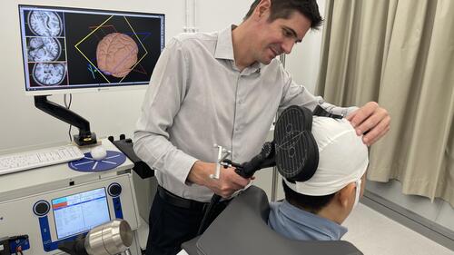 Dr. Ben Thompson uses a hand-held device to scan a patient's head at the CEVR lab.