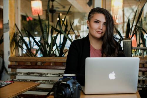A young woman sits behind a laptop.