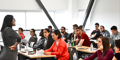 An instructor stands in front of a class of students.