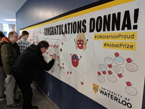 Attendees sign a congratulatory poster for Professor Donna Strickland.