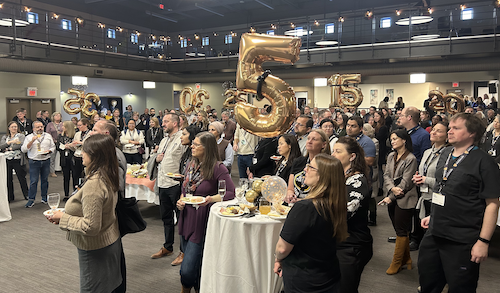Employees listen to a speaker at Fed Hall during the years of service event. Balloons indicate what anniversary year is being celebrated at what table.