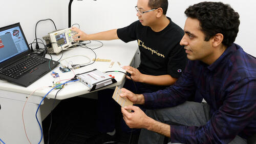 Two men work on a computer RFID tagging system.