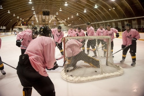 Warriors hockey players play in pink jerseys.