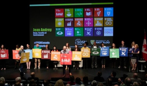 People on stage holding up UN sustainable development goal signs