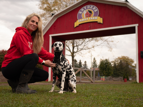 Meghan Snyder with a Dalmatian in front of the Snyders Family Farm gate.