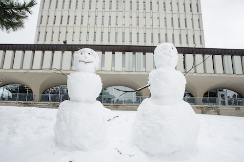 Two snowmen in front of the Dana Porter library.