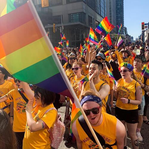 A colourful Pride parade image with Pride flags.