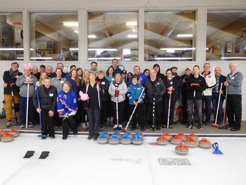 Participants of thr 2018 Hagey Bonspeil game pose and smile with their curling equipment.