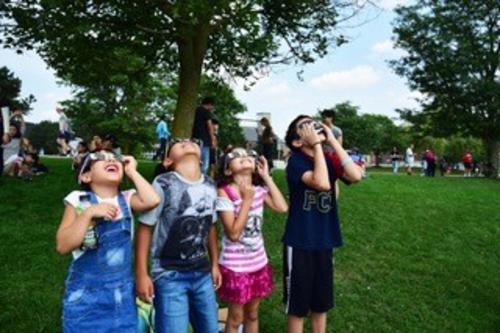 Children view eclipse through eclipse glasses