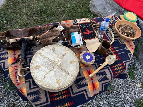 A drum and various Indigenous items on a blanket.