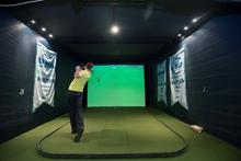 A man takes a swing in the golf simulator.