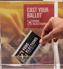 A person drops a ballot into a ballot box for the Feds elections.