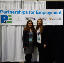 Two women stand in front of a Partnerships 4 Employment Banner.