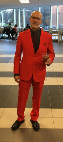 Terry Labach wearing a red suit and holding a beverage.