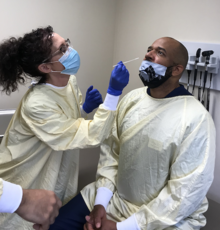 A clinic staff member prepares to administer a COVID test to Dr. Andre Stanberry.