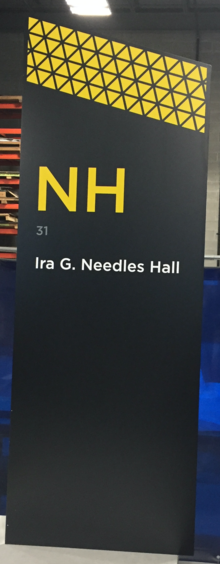 A wayfinding sign for Ira Needles Hall.